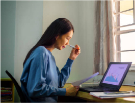 画像：窓際の室内で女性がパソコン見ながら仕事している様子。